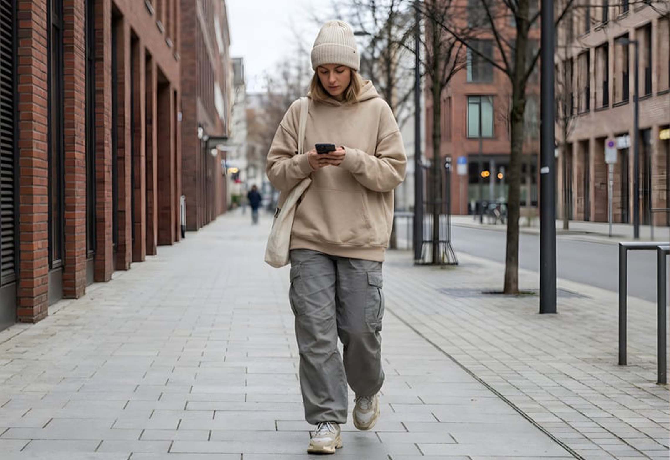 A person walking outdoors while looking at a mobile phone